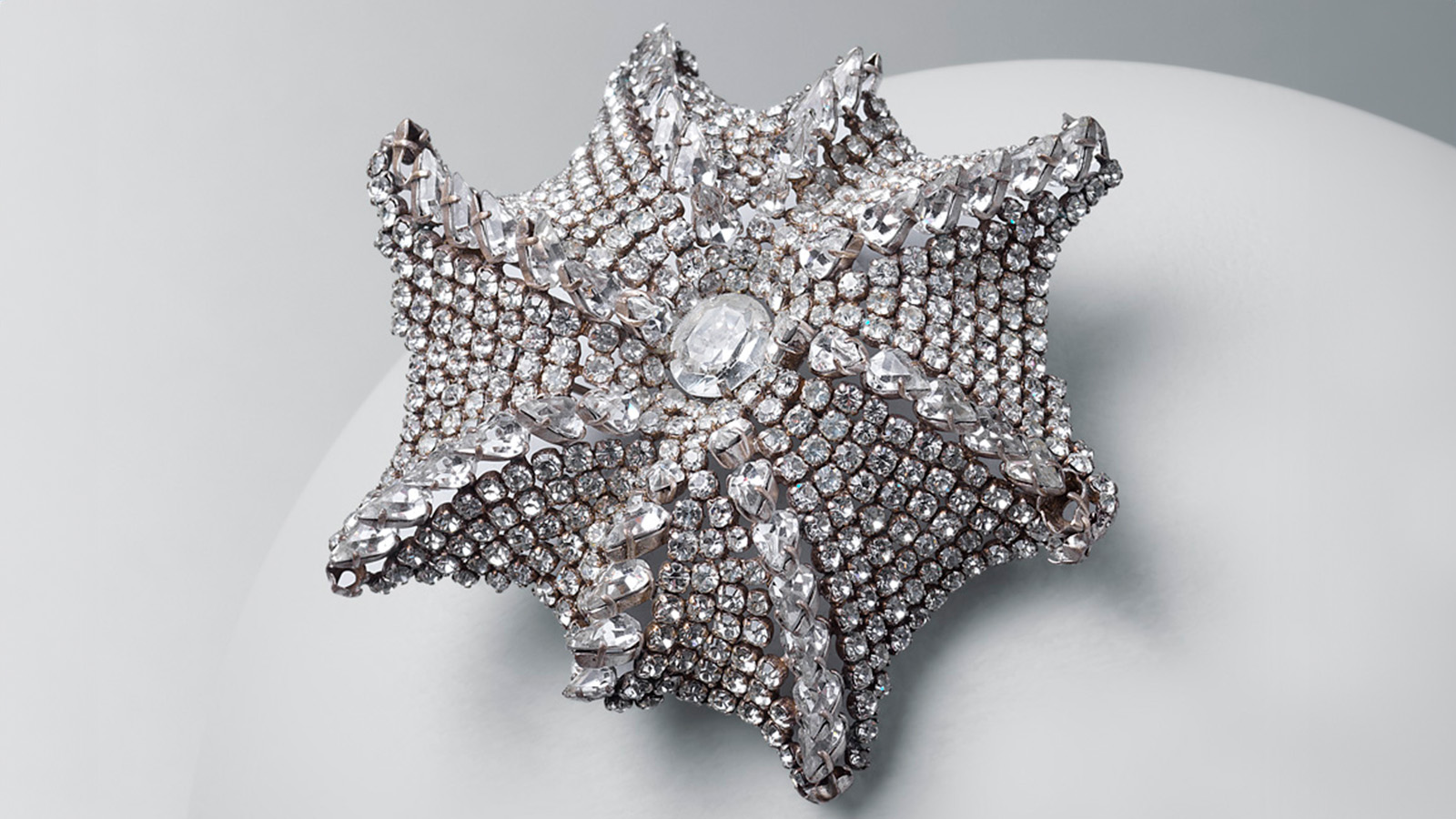 Spilla a forma di stella marina dal design asimmetrico, con otto nervature radiali di cristalli di taglio pera che si diramano da un cristallo ovale di Boemia © Cristobal Balenciaga Museoa Spilla a forma di stella marina dal design asimmetrico, con otto nervature radiali di cristalli di taglio pera che si diramano da un cristallo ovale di Boemia © Cristobal Balenciaga Museoa