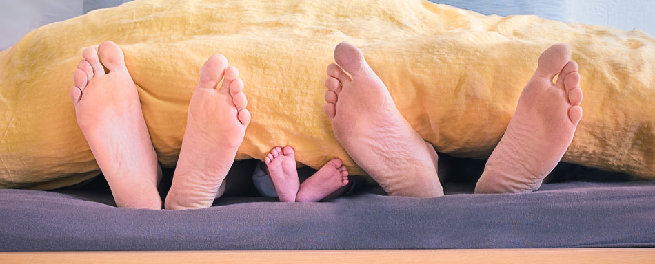 Pés de uma família sobressaindo da cama