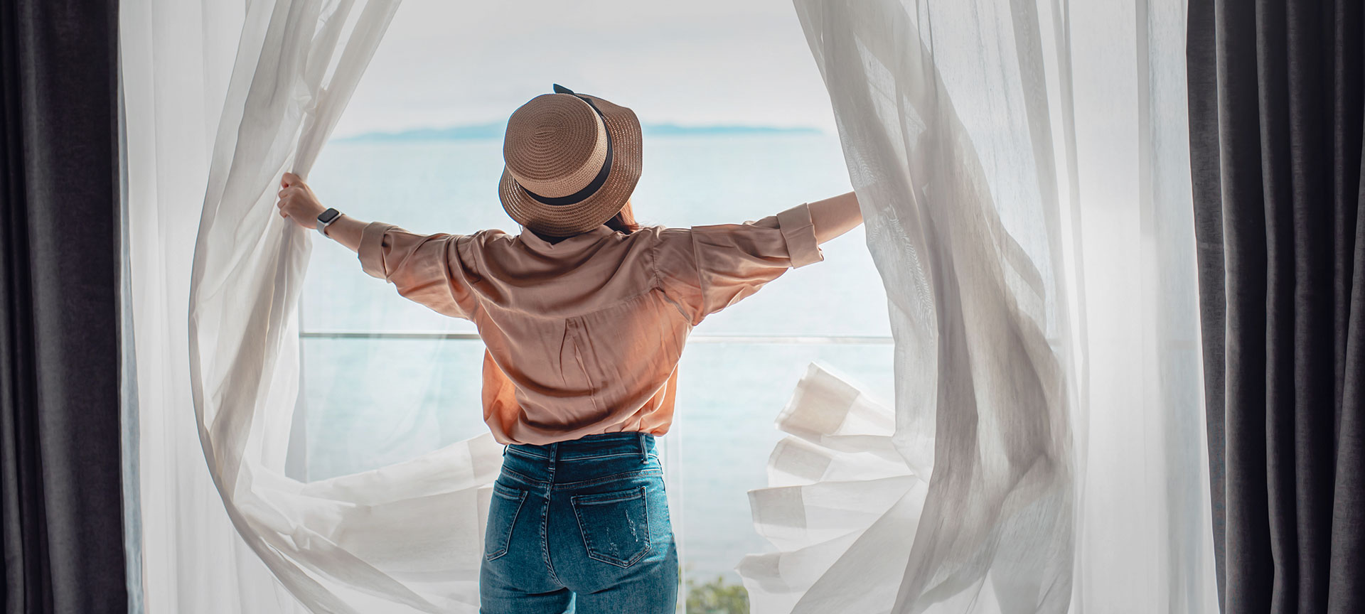 A tourist opening the curtains to their room A tourist opening the curtains to their room