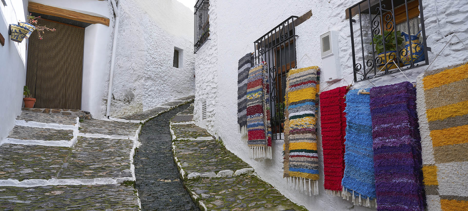 Typisch geschmückte Straße in Pampaneira (Granada) mit den traditionellen Decken der Alpujarra