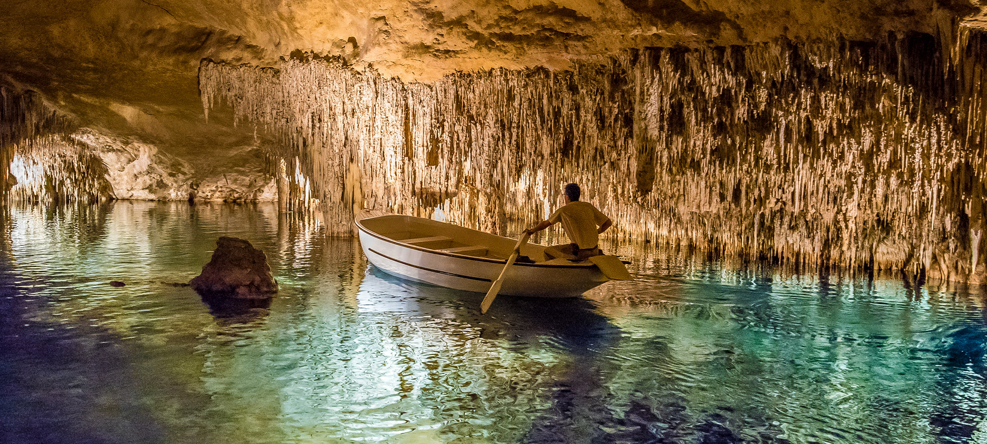 Homem numa lancha no interior das Cuevas del Drach (cavernas do dragão), em Maiorca.