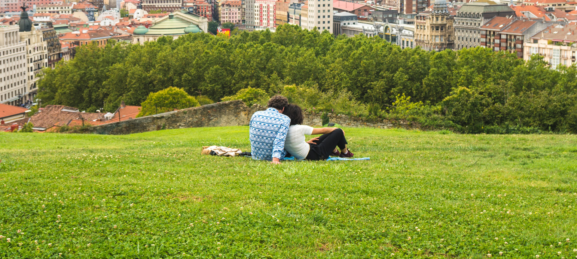 Un couple profite d'une magnifique vue panoramique sur Bilbao depuis un banc du parc de la colline qui surplombe la vieille ville