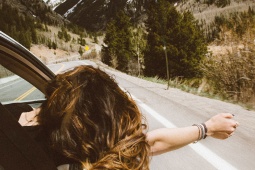 Una ragazza si affaccia dal finestrino di un’auto su una strada di montagna