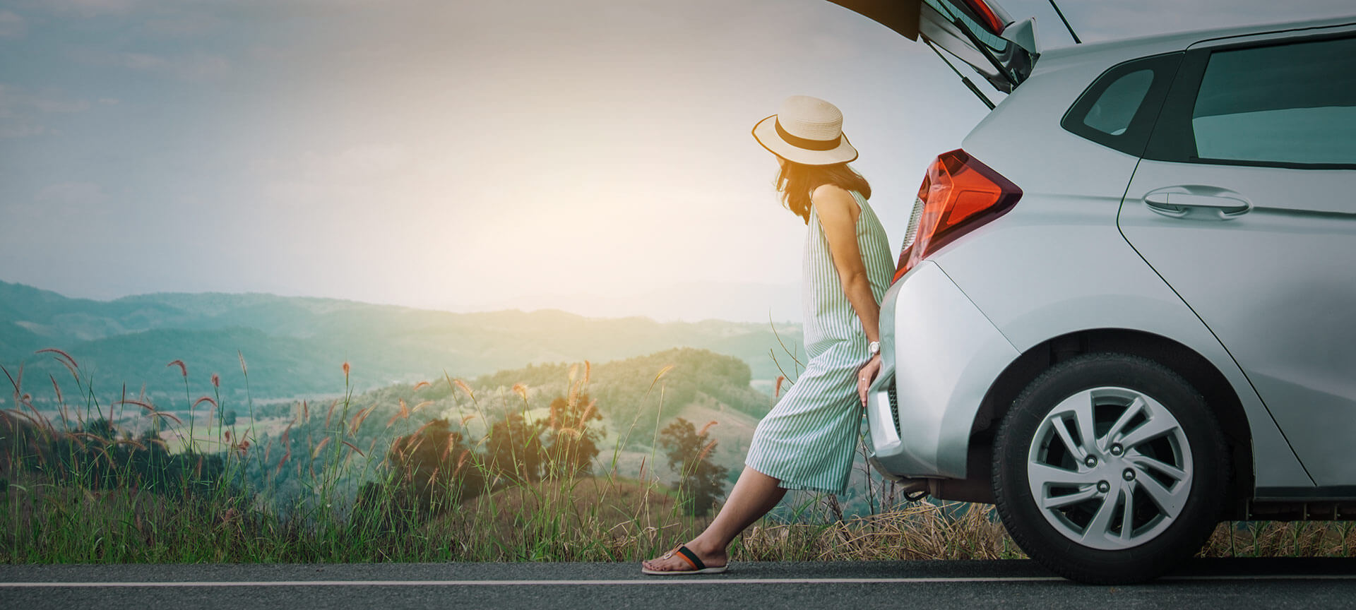 ドライブの途中、車に寄りかかって休憩をとる旅行者 ドライブの途中、車に寄りかかって休憩をとる旅行者