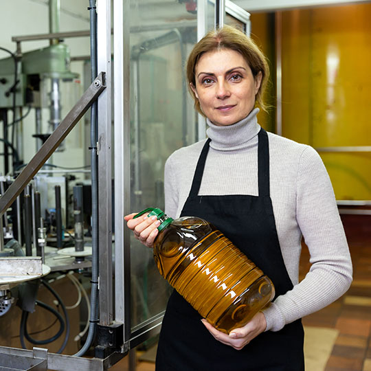 Donna che mostra una bottiglia di olio d'oliva in una fabbrica