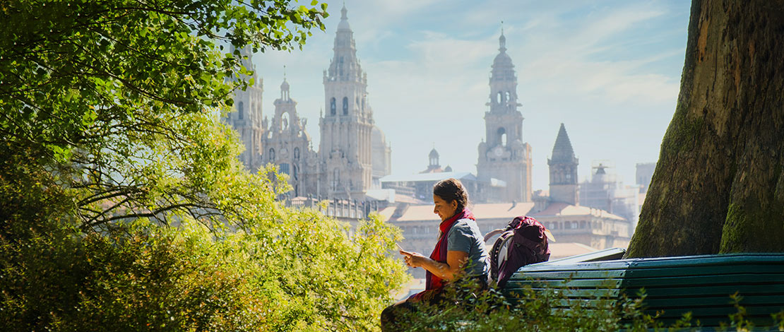 Peregrina sentada con vistas a la Catedral de Santiago de Compostela Peregrina sentada con vistas a la Catedral de Santiago de Compostela