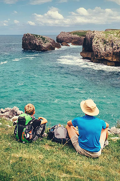 Des pèlerins se reposent en contemplant la côte sur le chemin de Compostelle du Nord Des pèlerins se reposent en contemplant la côte sur le chemin de Compostelle du Nord