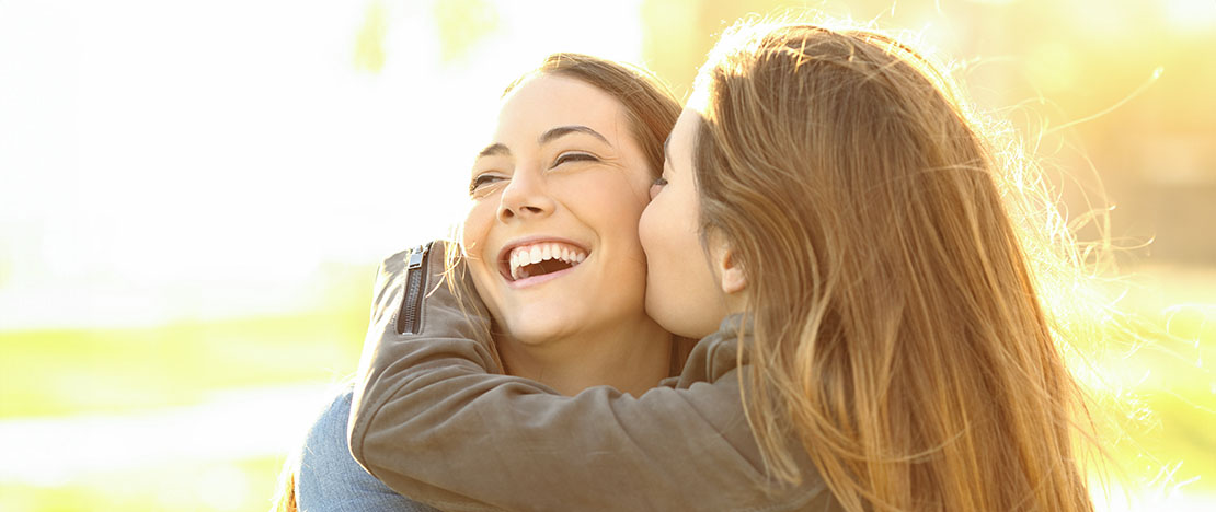 Female friends kissing each other on the cheek Female friends kissing each other on the cheek
