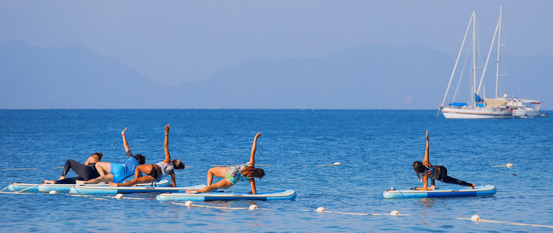 A group of people doing yoga on a SUP board.