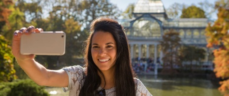 Woman taking a selfie in front of the Crystal Palace in Madrid, Region of Madrid Woman taking a selfie in front of the Crystal Palace in Madrid, Region of Madrid