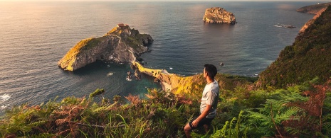 Tourist looking at San Juan de Gaztelugatxe in Bizkaia, Basque Country Tourist looking at San Juan de Gaztelugatxe in Bizkaia, Basque Country
