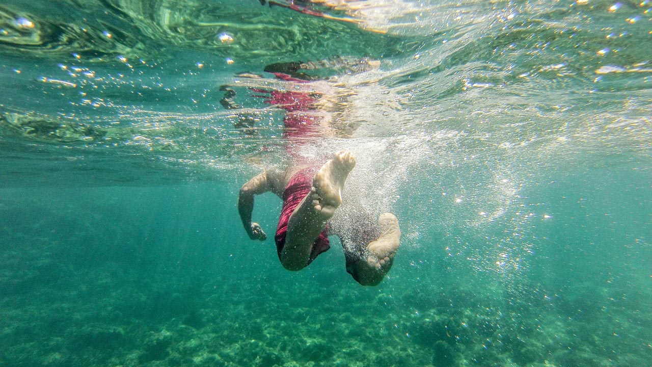 Uomo che nuota sott'acqua nel Mar Mediterraneo Uomo che nuota sott'acqua nel Mar Mediterraneo